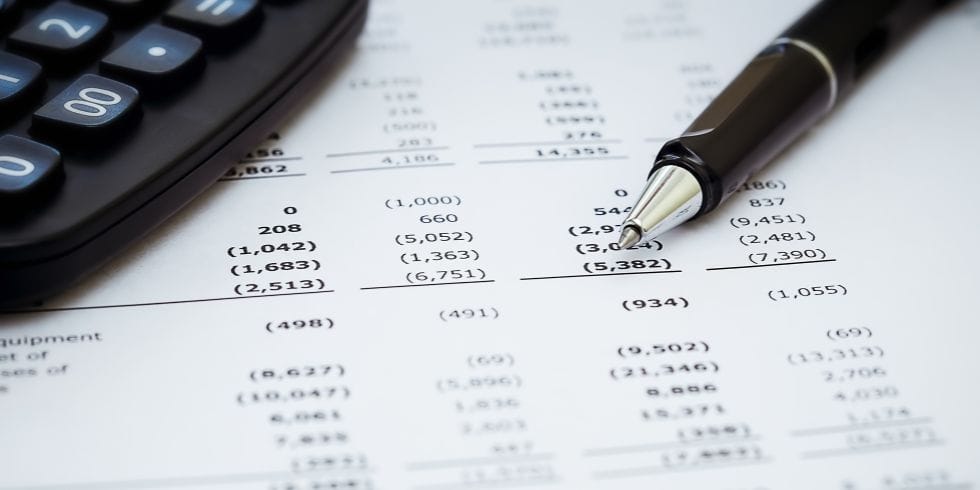 Financial Reports_980x490 Pen and calculator on top of financial report